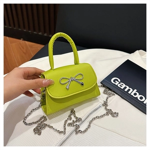 Détail du mini sac vert citron avec un nœud argenté et une bandoulière en chaîne
