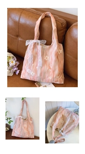 Detail of floral embroidery and white lace ribbon on pink gradient pleated tote bag