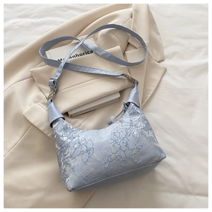 Détail du tissu jacquard brodé bleu clair et de la boucle argentée sur le sac à épaule