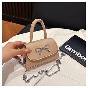 Détail d'un mini sac à bandoulière en cuir beige avec nœud en métal argenté et chaîne