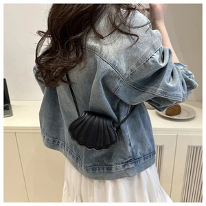Detail of a black shell-shaped crossbody bag with ribbed texture on a white background