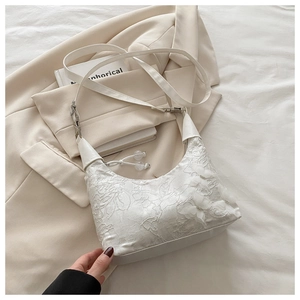Détail d'un sac à bandoulière en dentelle blanche avec broderie papillon 3D et boucle