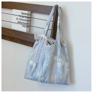 Detail of light blue tote bag featuring oversized lace bow and floral appliques