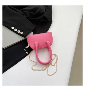 Close-up of rose pink lychee leather texture and gold chain on shell bag