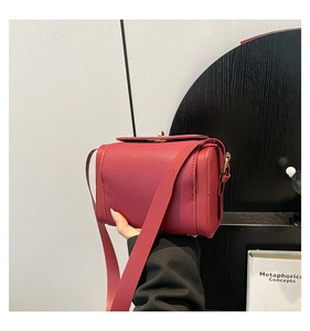 Détail du sac à main rouge en cuir grainé avec boucle métallique et bandoulière large