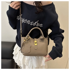 Détail du sac seau en cuir litchi kaki avec fermoir doré et pendentif d'ours
