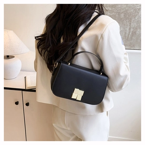 Détail d'un petit sac carré noir avec fermoir métallique carré doré de style minimaliste