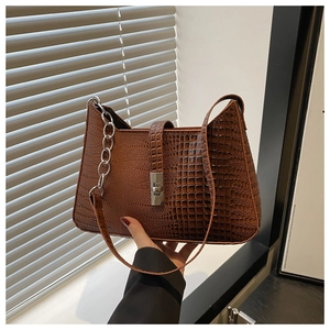 Detail of brown crocodile pattern shoulder bag with silver metal twist lock and chain strap
