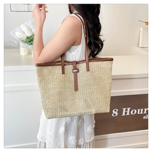 Detail of hollow straw tote bag with brown PU leather trim and long shoulder strap