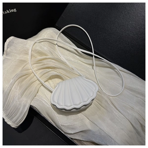 Detail of white shell-shaped mini bag with radial quilted texture on silk fabric