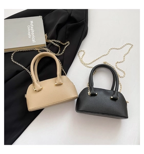 Detail of mini lychee texture dome bags in beige and black with golden chain straps