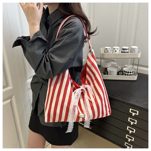 Close-up of red and white striped canvas tote with a white lace bow and handmade label