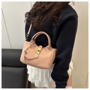 Détail du sac seau en cuir rose avec fermoir doré et breloque en forme de chien