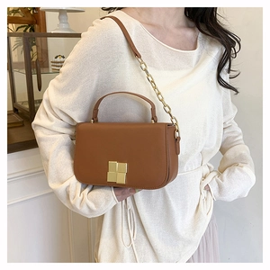 Gros plan du sac bandoulière en cuir marron avec chaîne dorée et boucle en métal