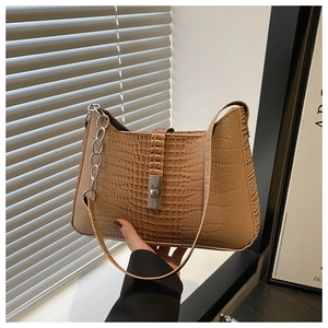 Detail of brown crocodile embossed shoulder bag with metallic chain and twist-lock closure