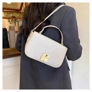 Détail du petit sac carré beige avec boucle métallique dorée porté par un modèle