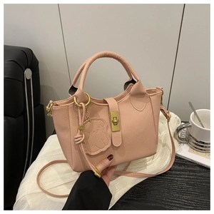 Détail du sac seau rose en cuir à motif litchi avec un joli pendentif en forme d'ours