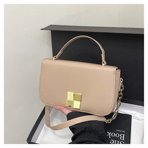 Détail du sac bandoulière café au lait avec fermoir doré dans une boîte cadeau