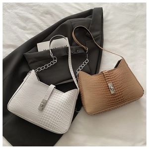 Detailed close-up of crocodile pattern texture on shoulder bags with silver chain straps