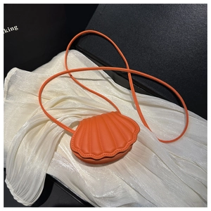 Macro shot of orange shell-shaped mini crossbody bag with textured faux leather surface