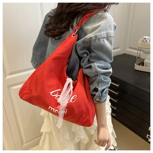 Detail of red nylon tote bag with white lettering and lace ribbon on a female model