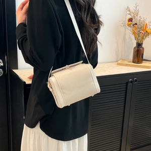 Sac boîte élégant en cuir blanc crème avec détails dorés porté par un modèle