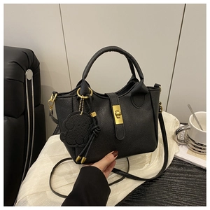 Détail du sac seau en cuir grainé noir avec fermoir rotatif doré et pendentif ours mignon