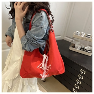 Detail of red tote bag with lace bow decoration and white Bonjour lettering