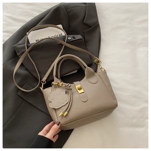 Detail of lychee pattern leather bucket bag with gold hardware and animal charm
