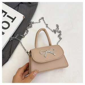 Détail du mini sac beige avec un nœud métallique argenté et une bandoulière à chaîne
