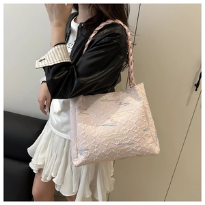 Detail of pink tote bag featuring geometric textures and colorful embroidery on the model