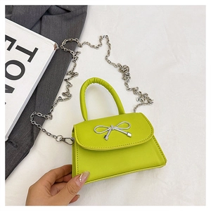 Détail d'un mini sac à main vert fluo avec nœud argenté et fine bandoulière chaîne