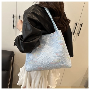 Detail of light blue tote bag with multi-color wave embroidery and woven strap