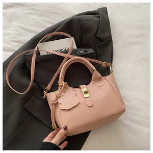 Detail of pink lychee leather bucket bag with gold lock and cute bear charm on blazer