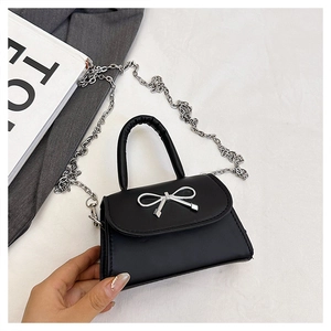 Détail du mini sac à bandoulière noir avec grande boucle nœud argentée et bandoulière chaîne