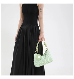Close-up of mint green pleated bubble texture bag with silver ring handle and floral charm