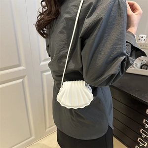 Chic white shell-shaped crossbody bag featuring textured faux leather and slim shoulder strap