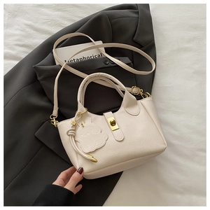 Detailed macro shot of the textured lychee leather bag with gold clasp and bunny charm