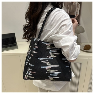 Detail of black canvas tote bag with colorful wave embroidery and rope handle on model