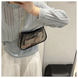 Close-up of transparent black PVC shoulder bag showing interior makeup and gold chain strap