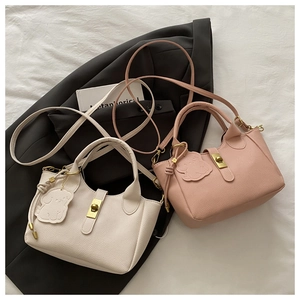 Close-up of pebble leather bucket bags in cream and pink with dog charms and metal clasps