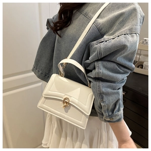 White faux leather tote bag with gold lock buckle and adjustable strap shown on model