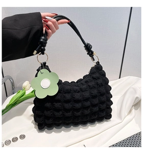 Detail of black popcorn texture shoulder bag featuring a light green floral charm decoration