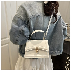 Detailed view of a white quilted crossbody bag with golden metal twist lock and wide handle