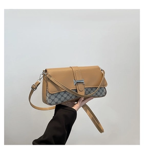 Detail of vintage patchwork crossbody bag featuring silver buckle and retro monogram pattern