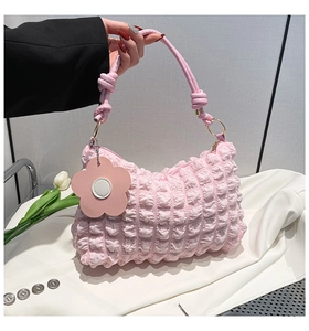 Detail of pink bubble textured fabric handbag with elegant knotted strap and flower charm