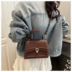 Brown leather handbag detail featuring a stylish gold round twist lock and flap closure