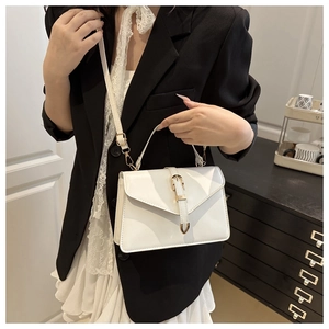 Detailed view of white faux leather bag with gold hardware and elegant buckle strap