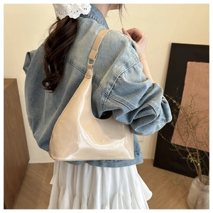Glossy beige patent leather hobo bag side view on model in a minimalist home setting
