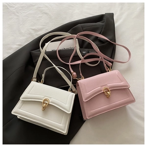 Detailed view of cream and pink faux leather crossbody bags with gold double-ring buckles